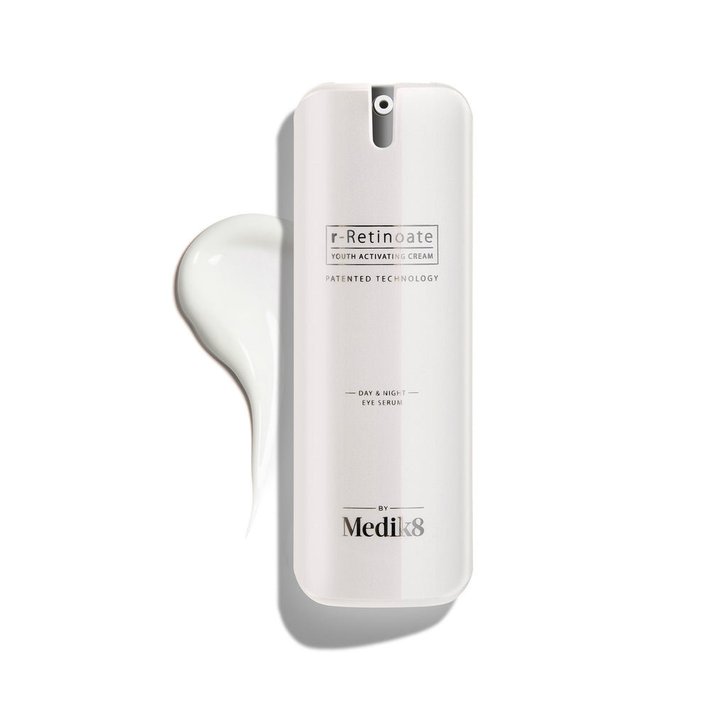 Botella blanca con dispensador de r-Retinoate Day & Night Eye Serum, con una gota del producto junto a ella.
