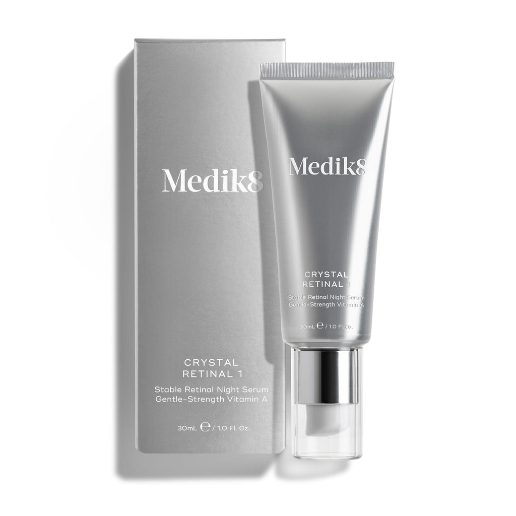 El tubo de Medik8 Crystal Retinal 1 descansa sobre una franja de sérum rosa pálido sobre un fondo blanco. Distintivos destacan «Ganador de los Get The Gloss Beauty Awards 2025» y «Primera tecnología patentada del mundo», junto con el texto: «El sérum facial dermatológico n.º 1 del Reino Unido*».
