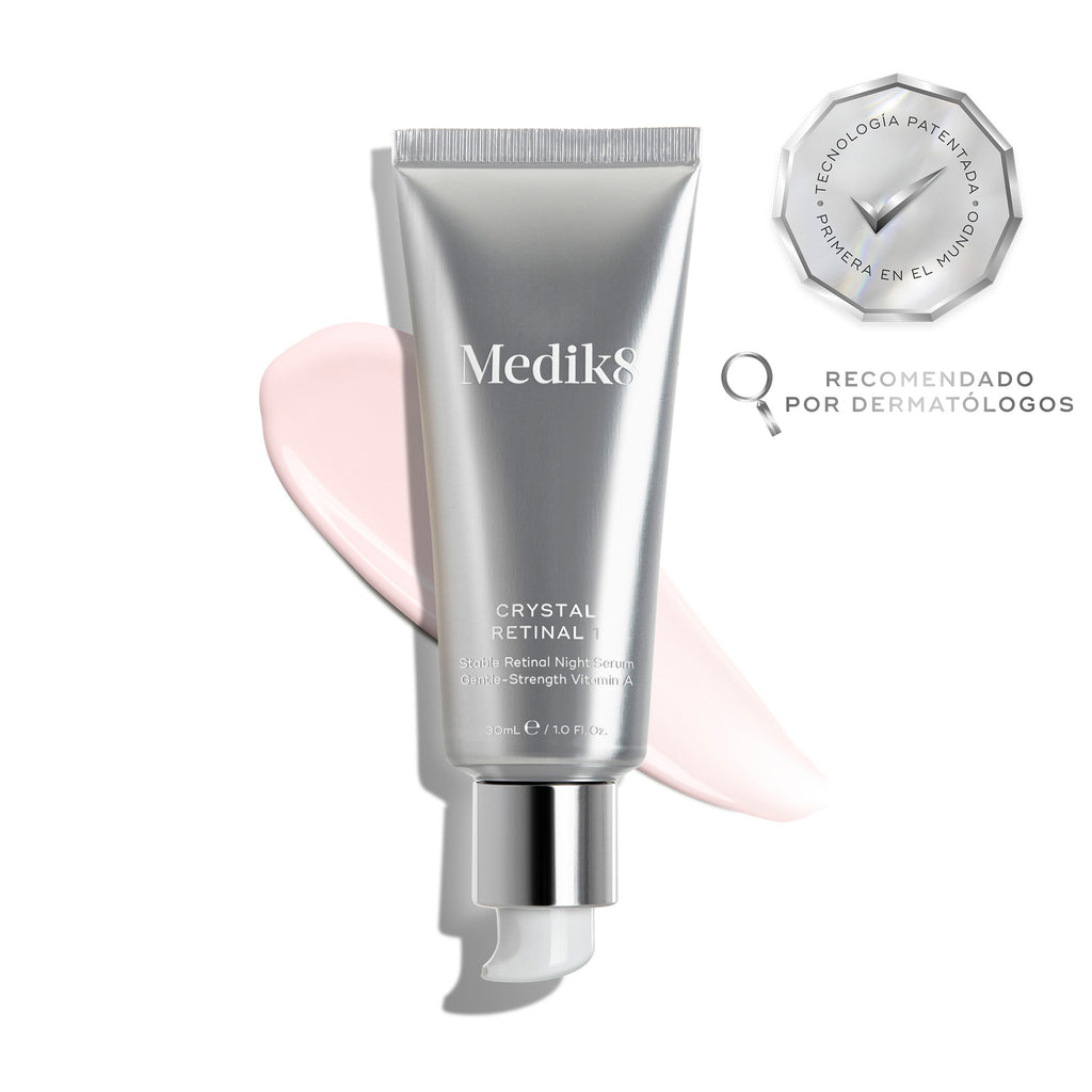El tubo de Medik8 Crystal Retinal 1 descansa sobre una franja de sérum rosa pálido sobre un fondo blanco. Distintivos destacan «Ganador de los Get The Gloss Beauty Awards 2025» y «Primera tecnología patentada del mundo», junto con el texto: «El sérum facial dermatológico n.º 1 del Reino Unido*».
