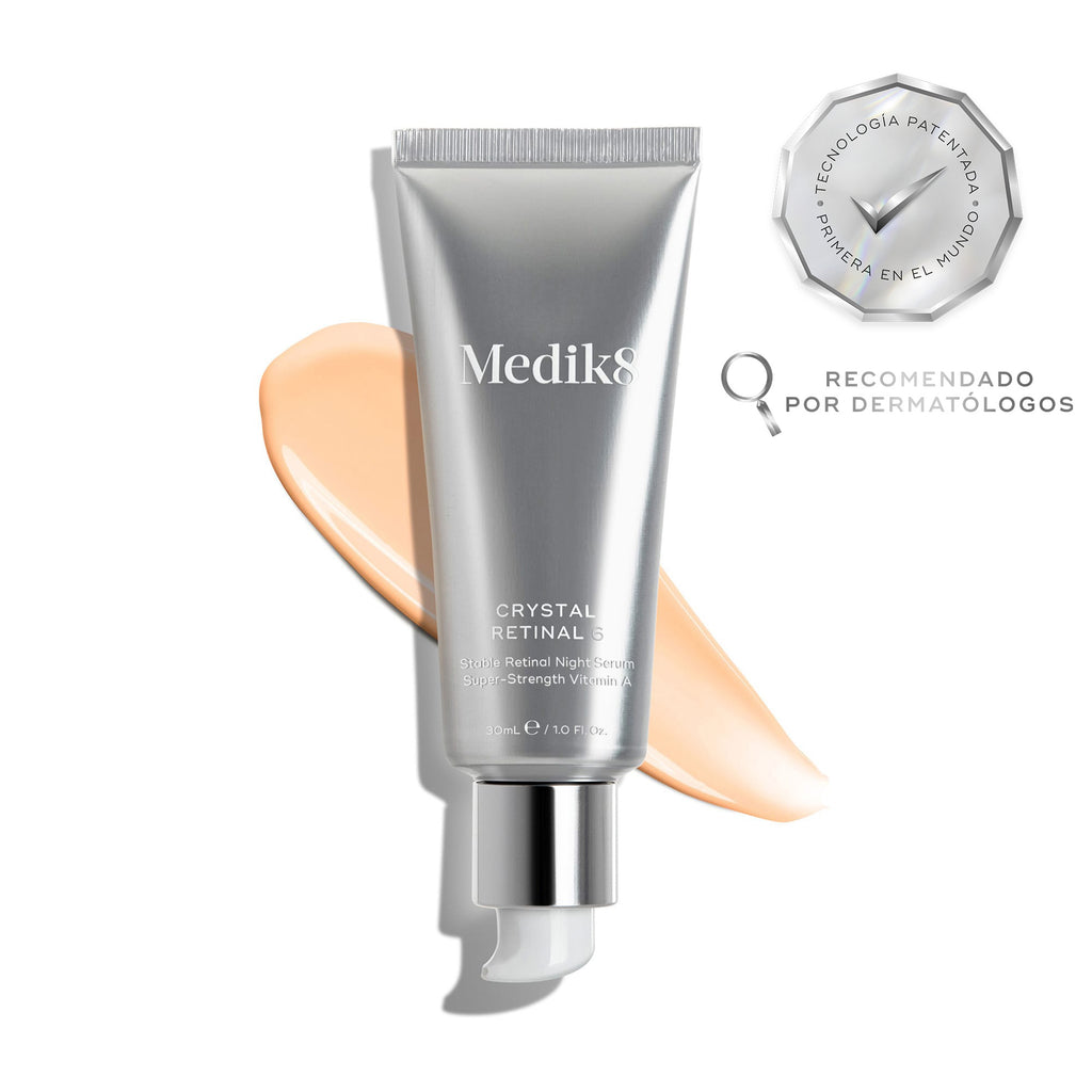 El tubo de Medik8 Crystal Retinal 6 descansa sobre una franja de sérum rosa pálido sobre un fondo blanco. Distintivos destacan «Ganador de los Get The Gloss Beauty Awards 2025» y «Primera tecnología patentada del mundo», junto con el texto: «El sérum facial dermatológico n.º 1 del Reino Unido*».
