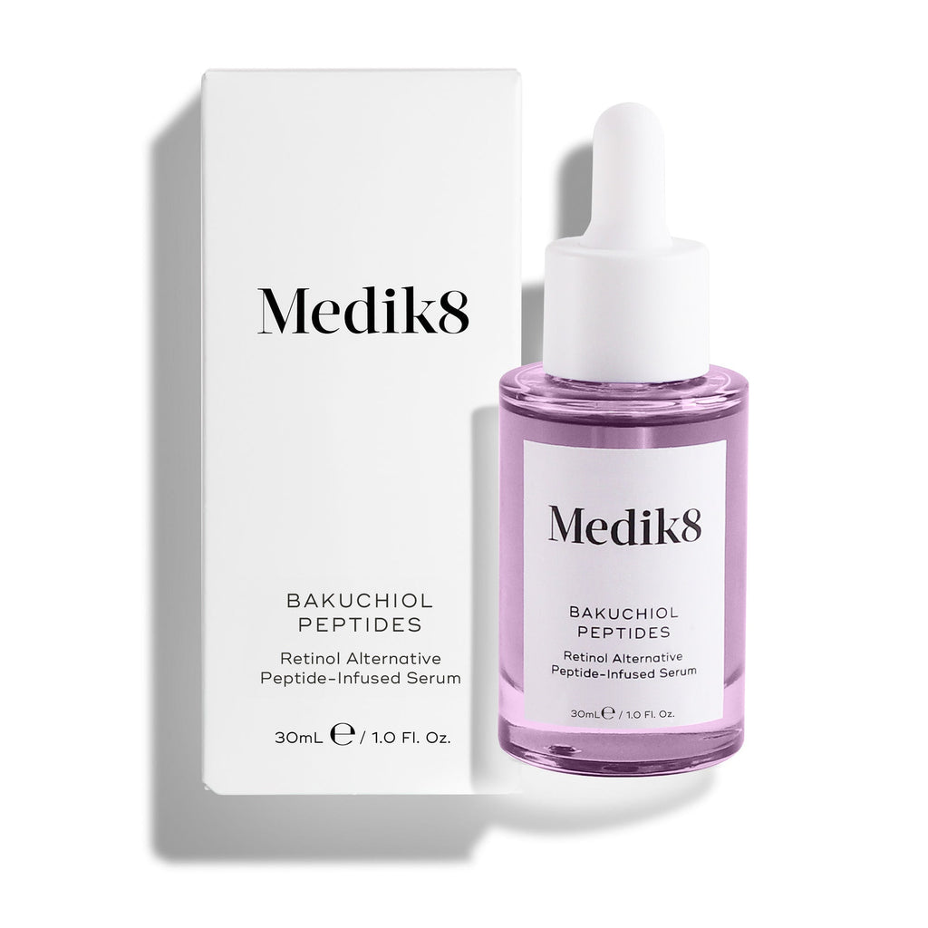 La botella del sérum Medik8 Bakuchiol Peptides, llena de líquido morado, se encuentra junto a su caja exterior blanca sobre un fondo blanco limpio. El texto del envase lo identifica como un “Sérum con péptidos, alternativa al retinol”.