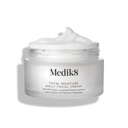 Tarro de vidrio esmerilado abierto de Medik8 Total Moisture Daily Facial Cream con un pico de crema blanca en la parte superior, colocado sobre un fondo blanco limpio. Los distintivos en las esquinas superiores indican que es «Ganador de los Daisy Beauty Awards 2025» y «Recomendado por dermatólogos».