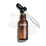 Packshot cenital de una botella de 30 mL de Medik8 C-Tetra Lipid Vitamin C Radiance Serum. La botella de vidrio ámbar está destapada y colocada en el centro, con su tapa negra con gotero apoyada diagonalmente detrás de ella. Un sérum líquido transparente está salpicado y extendido artísticamente sobre el fondo blanco limpio alrededor de la botella, con algunas gotas visibles en la pipeta de vidrio. La iluminación es brillante, proyectando sombras suaves hacia la izquierda y creando una estética clínica y el