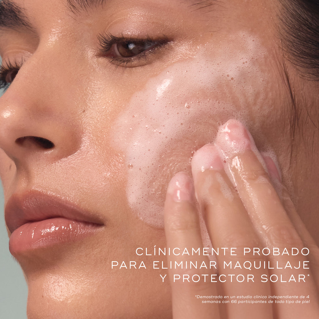 Primer plano de una mujer que se limpia el rostro con un gel espumoso, en el que se muestra la textura del producto y su aplicación, acompañado de un texto explicativo.