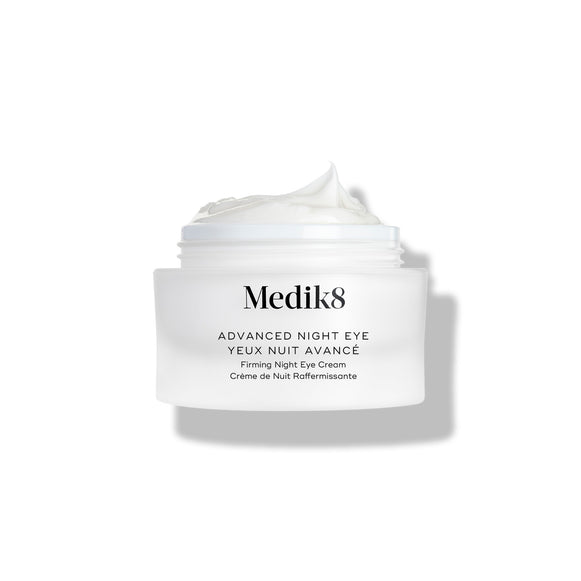 El tarro de crema para ojos Medik8 Advanced Night Eye aparece sobre un fondo blanco con la tapa retirada. La rica crema blanca es visible en el interior del tarro, destacando su textura.-25