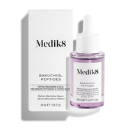 Sérum «Bakuchiol Peptides Retinol Alternative» de Medik8, que se muestra con su caja de embalaje blanca y un frasco cuentagotas transparente que contiene un líquido de color morado claro, sobre un fondo blanco impecable.