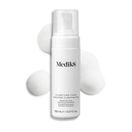 Botella con dispensador de Medik8 Clarifying Foam exhibida sobre un fondo blanco limpio junto a tres porciones de espuma blanca y ligera. El texto identifica el producto como un limpiador refrescante para imperfecciones con AHA/BHA de 150 mL.
