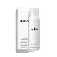 La botella con dispensador de Medik8 Clarifying Foam se encuentra junto a su caja exterior blanca a juego sobre un fondo blanco limpio. El texto en ambos identifica el producto como un limpiador refrescante para imperfecciones con AHA/BHA de 150 mL.
