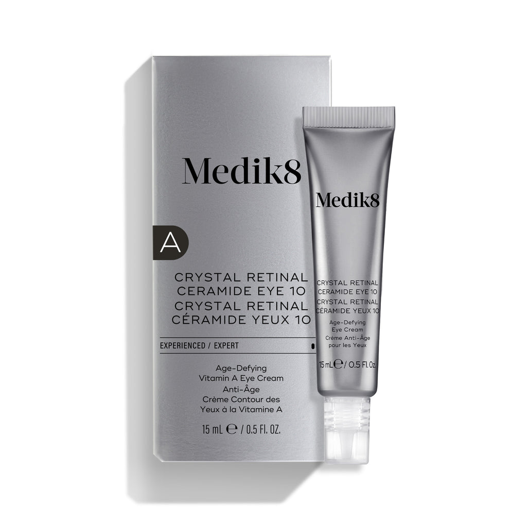 La crema para el contorno de ojos «Medik8 Crystal Retinal Ceramide Eye 10», mostrada con su caja de presentación plateada y blanca y un tubo a juego sobre un fondo blanco.