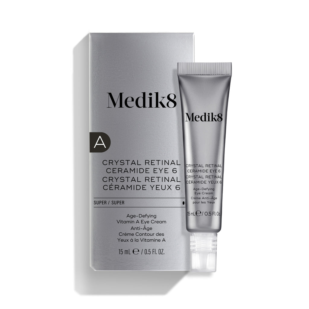 La crema para el contorno de ojos «Medik8 Crystal Retinal Ceramide Eye 6», mostrada con su caja de presentación plateada y blanca y un tubo a juego sobre un fondo blanco.