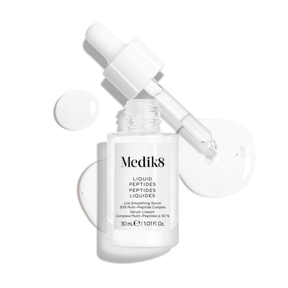 Un frasco cuentagotas de vidrio transparente del sérum Liquid Peptides se presenta con el cuentagotas retirado y colocado al lado, junto a gotas de sérum que muestran la textura del producto.-14