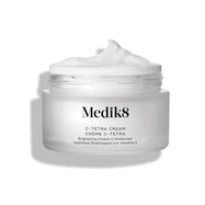 El tarro de crema C-Tetra Cream aparece abierto sobre un fondo blanco limpio con sombras suaves. El tarro de vidrio esmerilado blanco muestra el logotipo de Medik8 y la etiqueta “C-TETRA CREAM Lipid Vitamin C Radiance Cream” en formato de 50 mL. En la parte superior se ve un remolino espeso de crema blanca, destacando su textura hidratante.