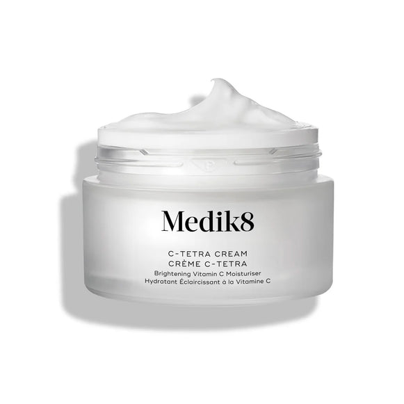 El tarro de crema C-Tetra Cream aparece abierto sobre un fondo blanco limpio con sombras suaves. El tarro de vidrio esmerilado blanco muestra el logotipo de Medik8 y la etiqueta “C-TETRA CREAM Lipid Vitamin C Radiance Cream” en formato de 50 mL. En la parte superior se ve un remolino espeso de crema blanca, destacando su textura hidratante.-24