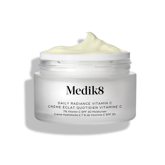 El tarro de cristal de Medik8 Daily Radiance Vitamin C aparece abierto con una generosa punta de crema amarillo pálido en la parte superior. El texto identifica el producto como una crema hidratante dos en uno C-Tetra Cream SPF 30 de 50 mL.-22