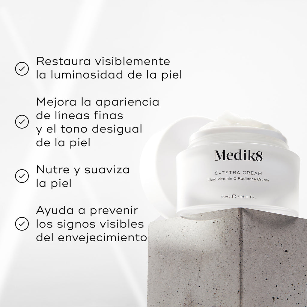 El tarro de C-Tetra Cream está colocado sobre un bloque de piedra gris con un fondo blanco iluminado por suaves rayos de luz. La imagen incluye cuatro afirmaciones con marcas de verificación:

Restaura visiblemente la luminosidad de la piel
Mejora la apariencia de líneas finas y tono desigual
Nutre y suaviza la piel
Ayuda a prevenir los signos visibles del envejecimiento