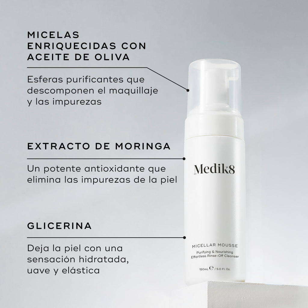 Una botella de Medik8 Micellar Mousse exhibida sobre un bloque blanco. Unas líneas conectan la botella con texto que explica los ingredientes clave: micelas infusionadas con aceite de oliva para descomponer el maquillaje, extracto de moringa para extraer las impurezas y glicerina para proporcionar hidratación.