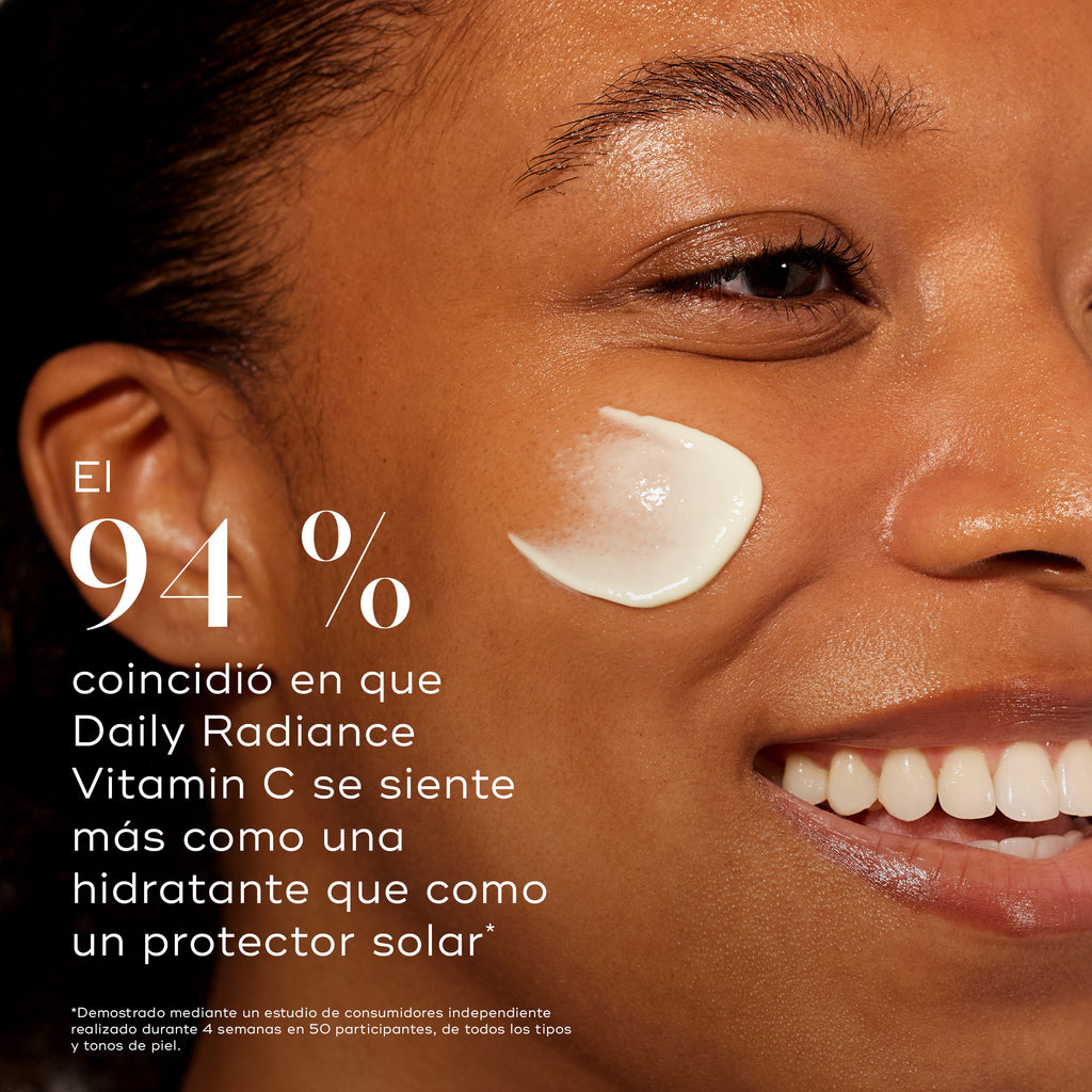 Primer plano de perfil de una modelo sonriente con una pincelada de crema en la mejilla. El texto en negrita afirma que el 94 % sintió que Daily Radiance Vitamin C se siente más como una crema hidratante que como un protector solar.