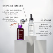 Botellas de Medik8 Hydr8 B5 Intense y Hydr8 B5 colocadas sobre pedestales blancos sobre un fondo limpio y luminoso. El texto enumera los beneficios de HYDR8 B5 INTENSE como «para una hidratación intensiva y de larga duración» y «ideal para pieles normales a deshidratadas». Los beneficios de HYDR8 B5 incluyen «hidratación ligera diaria» e «ideal para pieles normales a sensibles».
