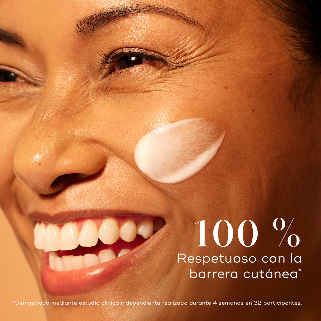 Mujer sonriente con una piel radiante y una aplicación de sérum Medik8 C-Tetra Advanced en la mejilla, destacando un 0 % de alteración de la barrera cutánea para una luminosidad suave pero eficaz.