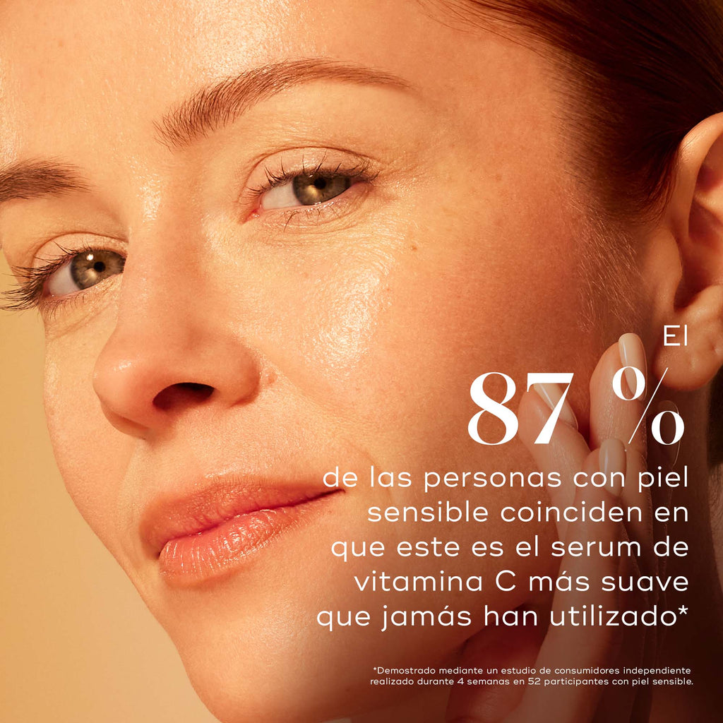 Para Reino Unido: Primer plano de una mujer con una tez luminosa y radiante apoyando la mano sobre la mejilla. El texto dice: “El 87 % de las pieles sensibles está de acuerdo en que este es el sérum de vitamina C más suave que han usado.” Un texto más pequeño debajo indica que los resultados se basan en un estudio de consumidores.